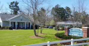 A one story apartment building with green grass and a sign