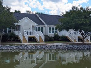 A one story apartment building with white railings in front of a pond