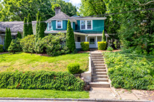 Green house with stairs leading from street to front door.