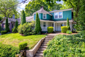 Green house with stairs leading from street to front door.