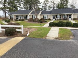 One story apartment building with bushes and sidewalks