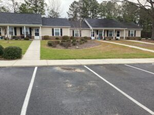 A one story apartment building with bushes and sidewalks