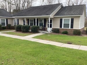 A one story apartment building with grass and a sidewalk