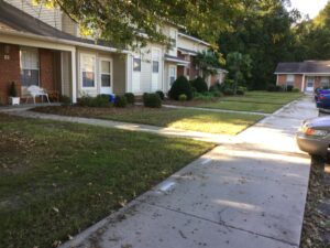 An apartment building with a sidewalk and green grass