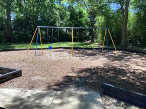 A swing set with mulch infront of green grass