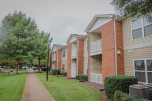 A two story apartment building with trees and green grass