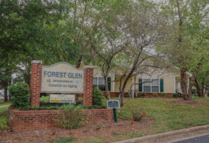 The entrance to a apartment community with trees and a sign