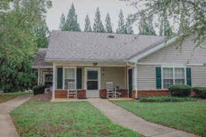 A one story apartment building with a porch and green grass