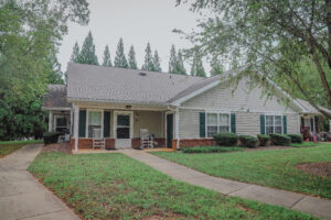 A one story apartment building with a porch and green grass