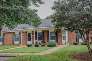 A one story brick apartment building with a green lawn