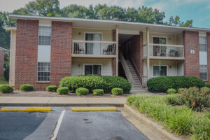 A two story brick apartment building with green landscaping