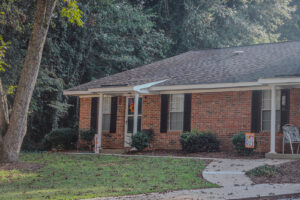 A one story brick apartment building with a green grass lawn