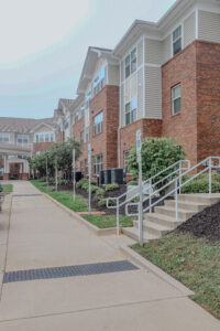 A three story apartment building with a sidewalk