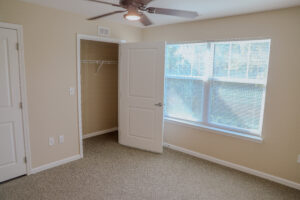 A bedroom with two windows and the closet open