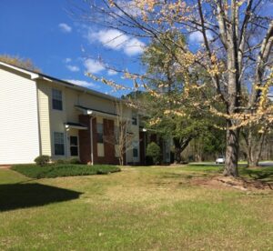 A two story apartment building with grass and trees