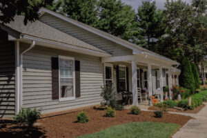 Single story apartment with mature trees and landscaping and front porch