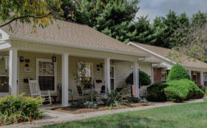 Single story apartment with mature trees and landscaping and front porch