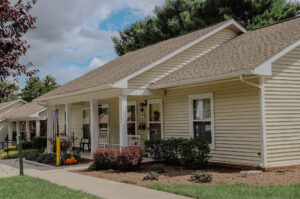 Single story apartment with mature trees and landscaping and front porch