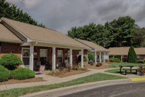 Single story apartment with mature trees and landscaping and front porch