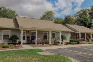 Single story apartment with mature trees and landscaping and front porch