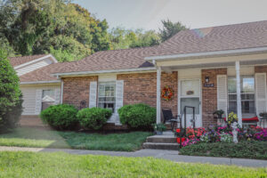 Single story apartment building with covered front porch and potted plants