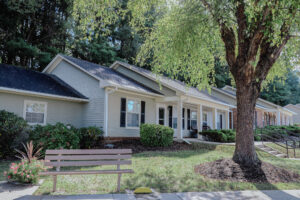 Single story apartment with bench out front and mature trees