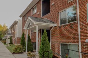 A three story brick apartment building with a small stoop