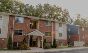 A three story apartment building with trees behind it