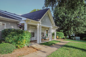 A one story building with bushes and green grass