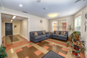 Communal seating area with two couches, tile floor and potted plants