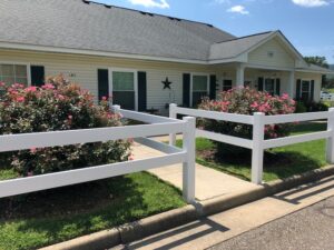 A one story apartment building with a white fence