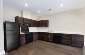 Kitchen with brown cabinets, black appliances and white counter tops