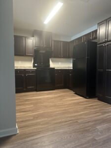 A kitchen with dark brown cabinets and laminate flooring