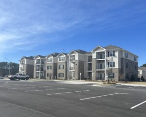 A three story apartment building and a parking lot