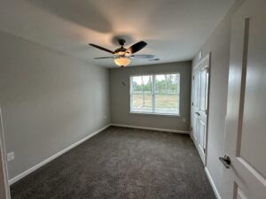 A bedroom with windows and a fan