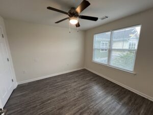 A bedroom with two windows and a ceiling fan