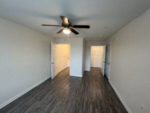 A bedroom with cream wall and a ceiling fan