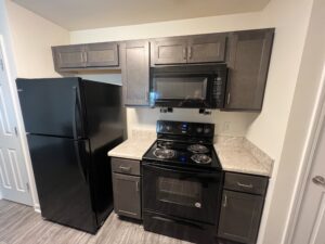 A kitchen with black appliances and brown cabinets