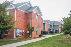 Green and brick two story apartment complex with trees