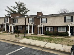 A two story apartment building with grass and a sidewalk