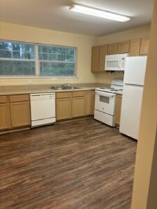 A kitchen with wood flooring and white appliances