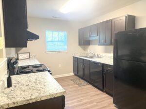 Kitchen with dark brown cabinets, black appliances and white counter tops