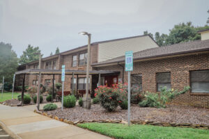 A two story brick apartment building wth rose bushes