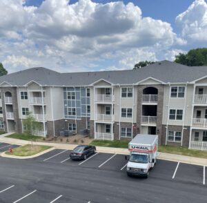 A three story apartment building with a parking lot